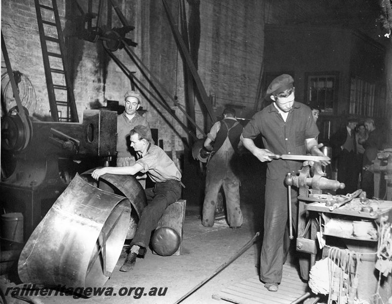 P20453
Steam loco dome, on belt driven hammer, coppersmith, Mr Taylor, apprentice filing a job held in leg vice, other workers, Midland workshops, ER line, interior view
