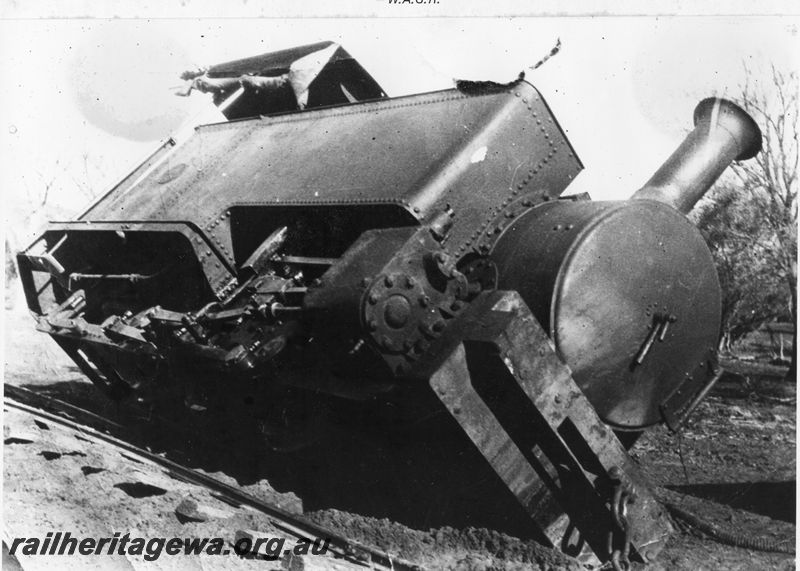 P20482
Derailment scene, gold mine loco on its side, rails collapsed, side and front view from trackside 
