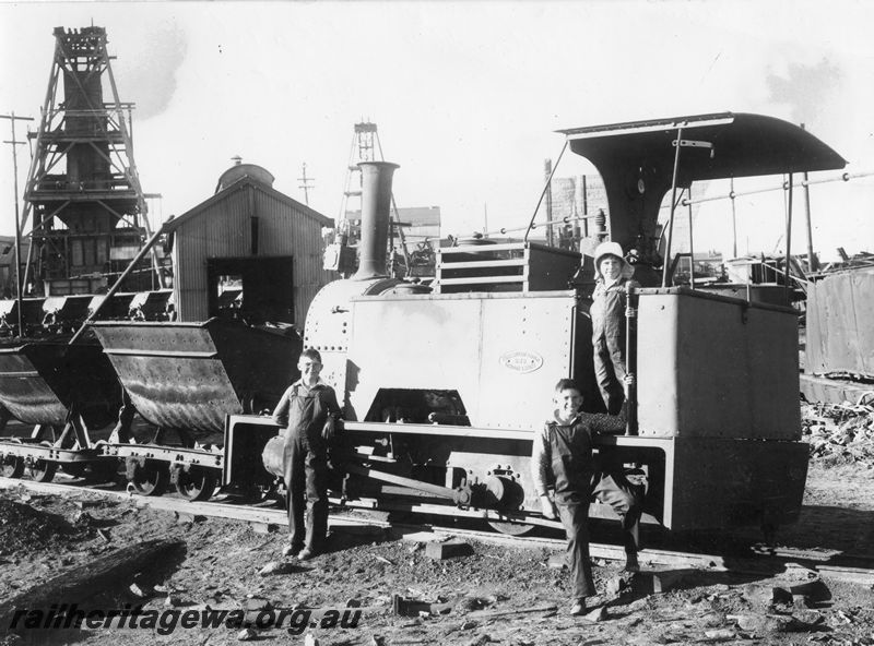 P20493
Great Bolder Gold Mine Kerr Stuart loco No 2, on ore train, near Hamilton Shaft, Golden Mile, Kalgoorlie, with boys posing for photo, mine buildings, derricks, side and end view

