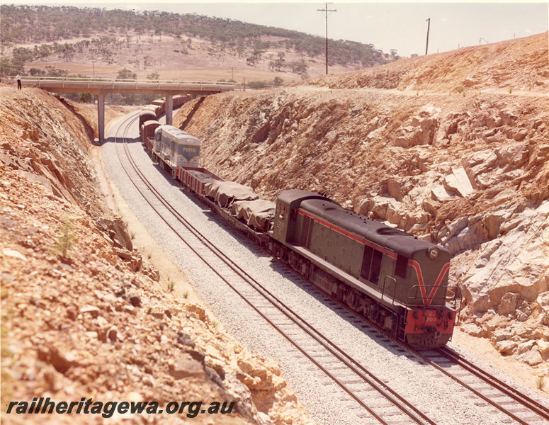 P20508
C Class 1703, on goods train to Midland, including vans, wagons, and K Class 201 on narrow gauge transfer bogies, passing under road bridge near Toodyay, Avon Valley line, side and front view from elevated position
