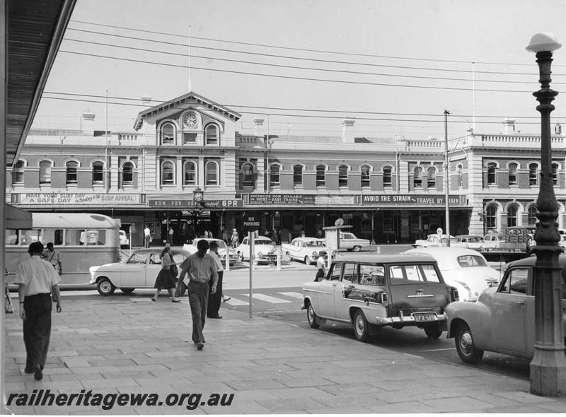 P20551
Entrance to Perth Railway Station building, clock, tram (part), carpark, cars, pedestrians, view from footpath in Forrest Place   
