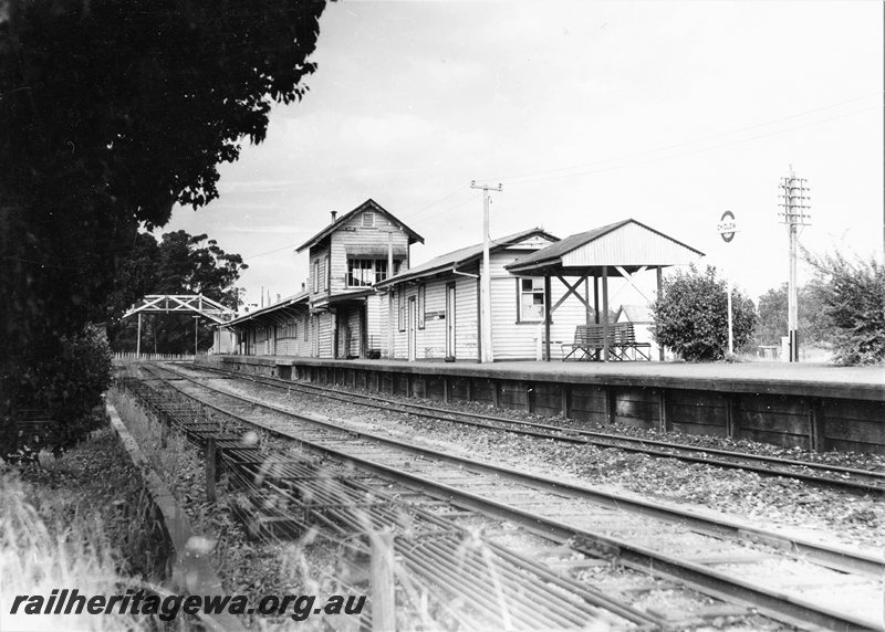 P20697
Station buildings, signal box, overhead footbridge, platform, station sign, shelter, seats, rodding, tracks, Chidlow, ER line, view from track level
