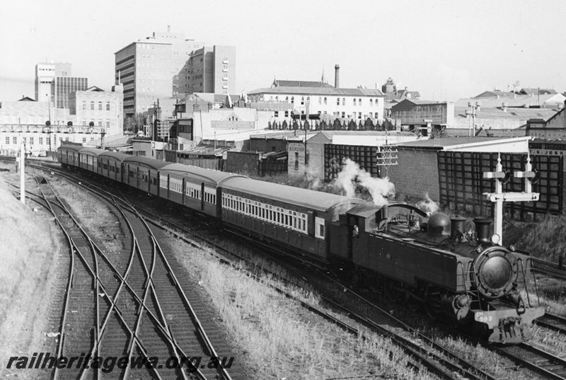 P20800
DD class 593 on a train of mixed suburban carriages, arriving Perth station, scissors crossover, gantry signals, bracket signals, city buildings in background, Perth ER line, side and front view from elevated position
