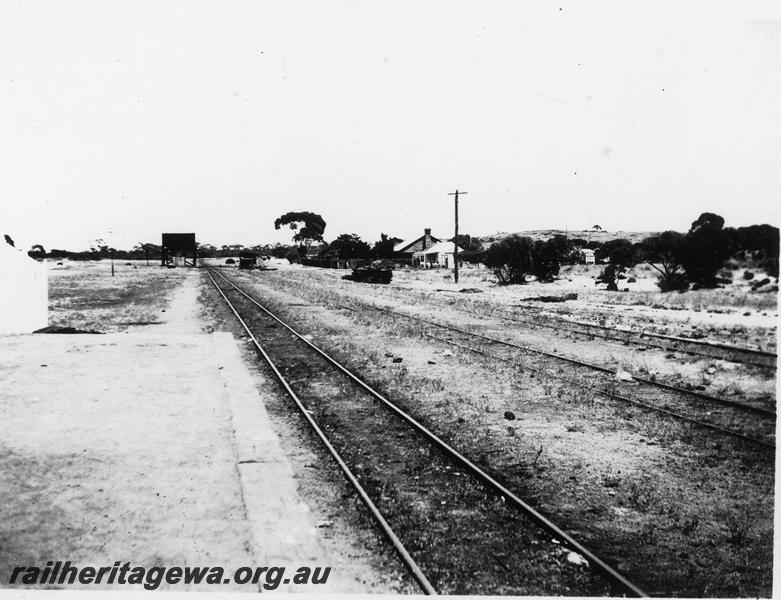 P21084
Platform, track, 25,000 gallon cast iron tank on a water tower, sidings, stone platelayers and single men's cottages, Yellowdine, EGR line, view looking west, c1940
