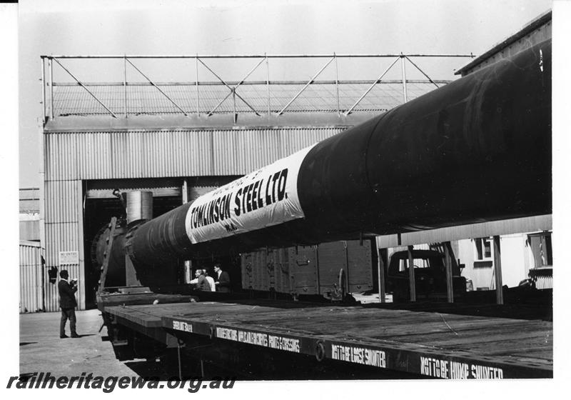 P21087
Rake of flat wagons, loaded with long Tomlinson steel chimney, shed, onlooker,  Welshpool, SWR line, trackside view
