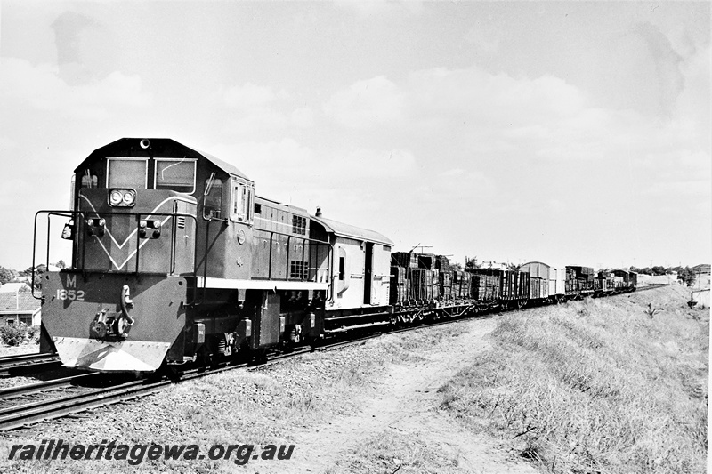 P21288
M class 1852 on goods train comprising mainly loaded timber wagons, Bayswater, ER line, front and side view
