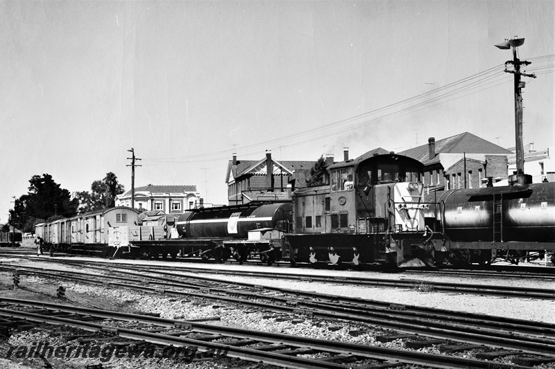 P21296
TA class 1811, shunting various wagons, vans, tank wagons, points, point lever, town buildings in background, Narrogin, GSR line, side and end view
