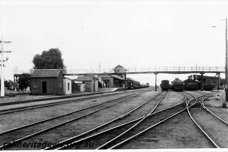 P21303
Station buildings, signal box, platform, train at station, bracket signals, pedestrian overpass, goods shed, yard, sidings, points, Merredin, EGR line, track level view
