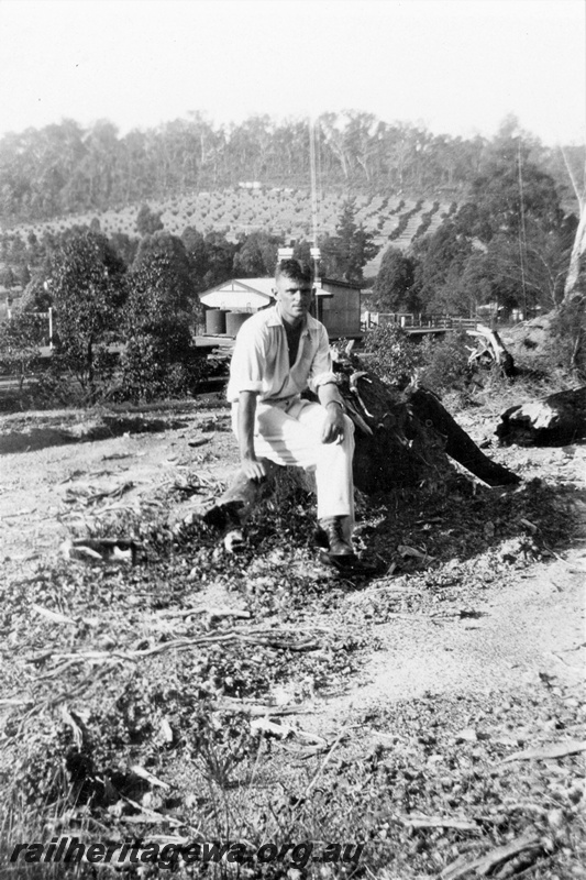 P21368
Clifford Goss, WAGR Assistant Engineer, seated near cottage with water tanks, fields in background, Parkerville, Eastern Railway deviation, ER line, c1932-1934
