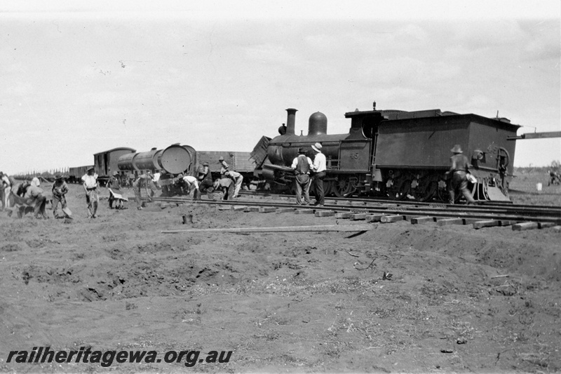 P21375
PWD G class 45 loco, wagons, derailed  at the 328 mile, 28 chain location on the Wiluna Railway, NR line,   wagons of permanent way train off track, repairs under way by workers, supervisors, construction of Meekatharra to Wiluna section, NR line, date of derailment 12/11/1929, side and rear view.
