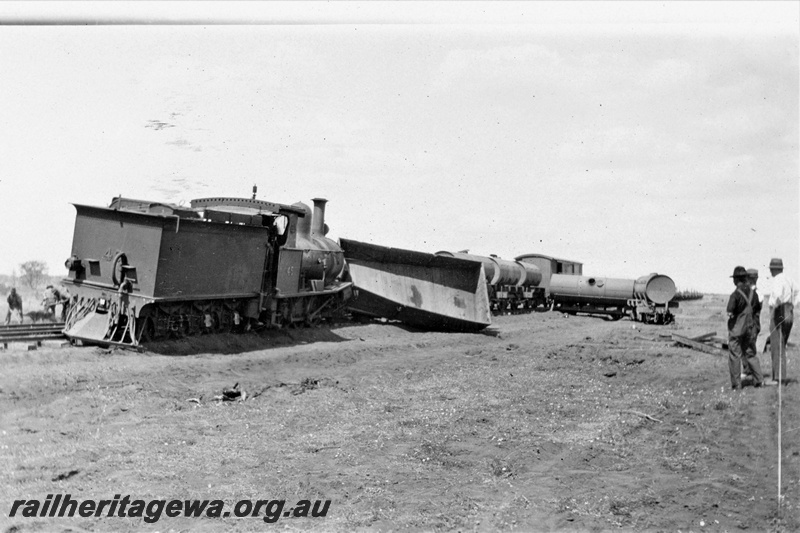 P21376
PWD G class 45 loco derailed at the 328 mile, 28 chain location on the Wiluna Railway, NR lin, wagons of permanent way train off track, repairs under way by workers, supervisors, construction of Meekatharra to Wiluna section, NR line, rear and side view. Date of derailment 12/11/1929
