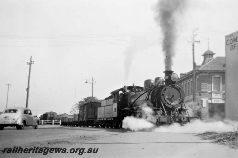 P21386
Midland Railway Co of Western Australia (MRWA) C class 18 on goods train, crossing Great Eastern Highway, shops, car, Midland, MR line, side and front view
