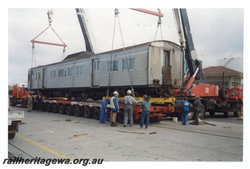P21437
ADK class 681, being lifted onto Brambles low loader, crane cables, workers, side and end view
