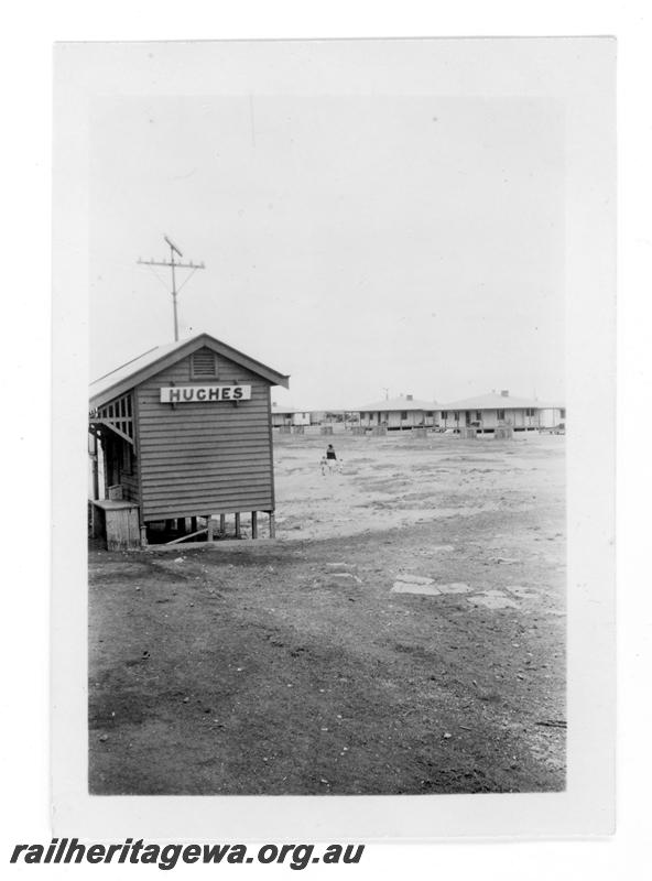 P21465
Station building, houses, woman and two children, Hughes, TAR line, ground level view
