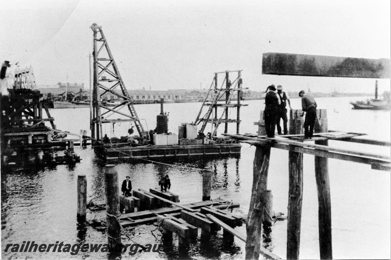 P21472
Wood trestle rail bridge over Swan River, being rebuilt after washaway, floating derrick, workers, Fremantle, ER line, view from North Fremantle bank 
