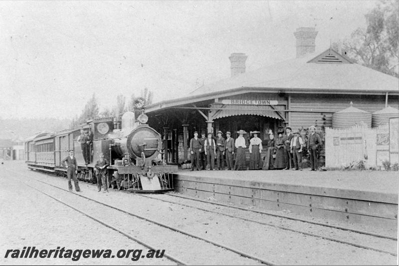 P21524
O class loco on mixed train, standing at station, station building, platform, canopy, mixed group of people on platform, crew, tracks, picket fence, water tanks, Bridgetown, PP line
