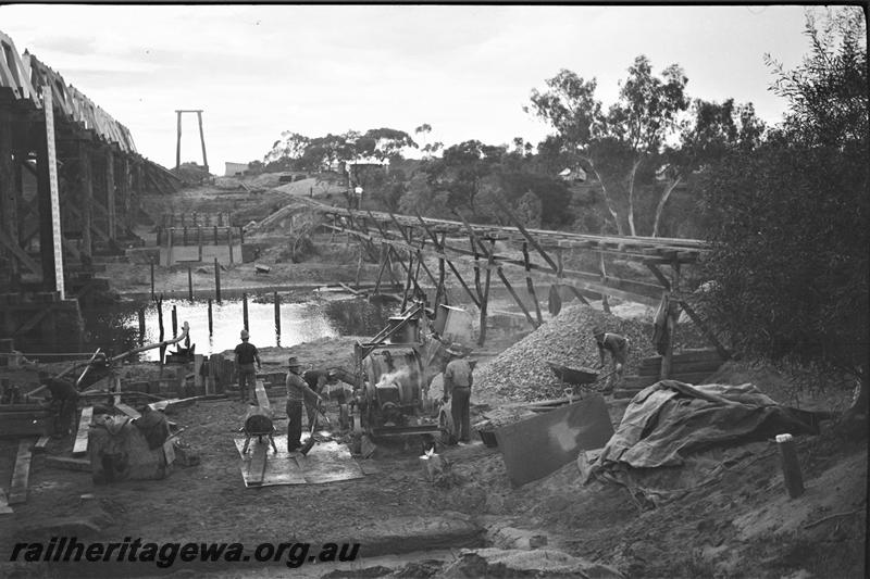 P21571
Construction of bridge foundations, machinery, workers, construction track across Greenough River, Eradu, NR line, view from bank
