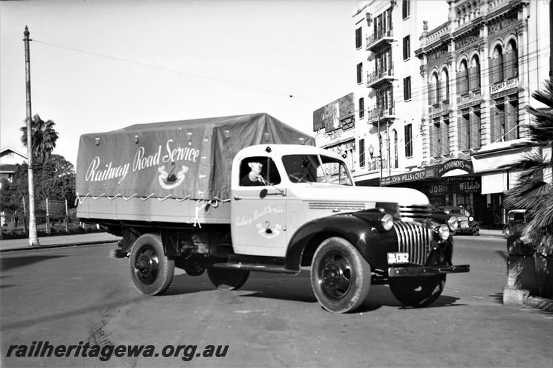 P21583
Railway Road Service utility truck with tarpaulin covering tray, licence number 1362, driver, in front of John Wills shop, side and front view 
