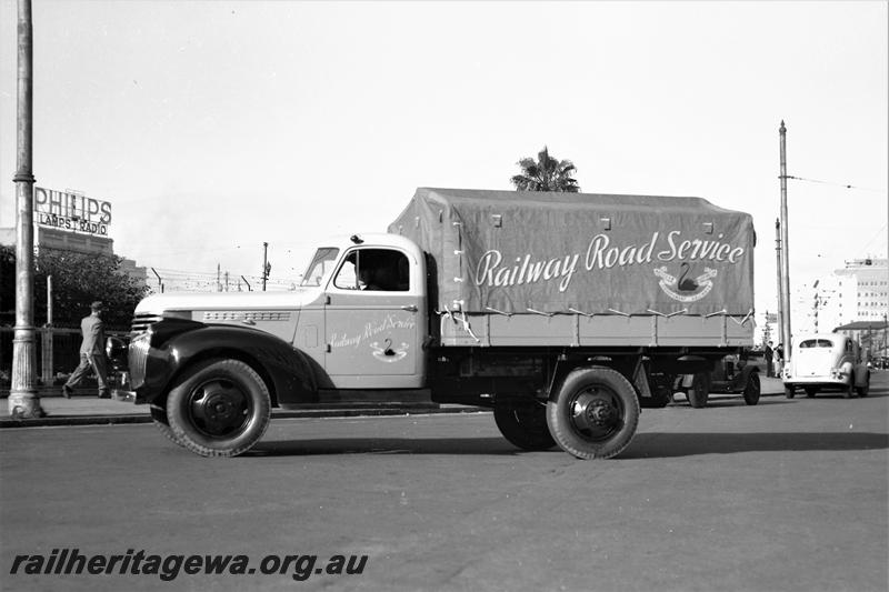 P21584
Railway Road Service utility truck with tarpaulin over tray, pedestrians, Philips advertising sign, side view
