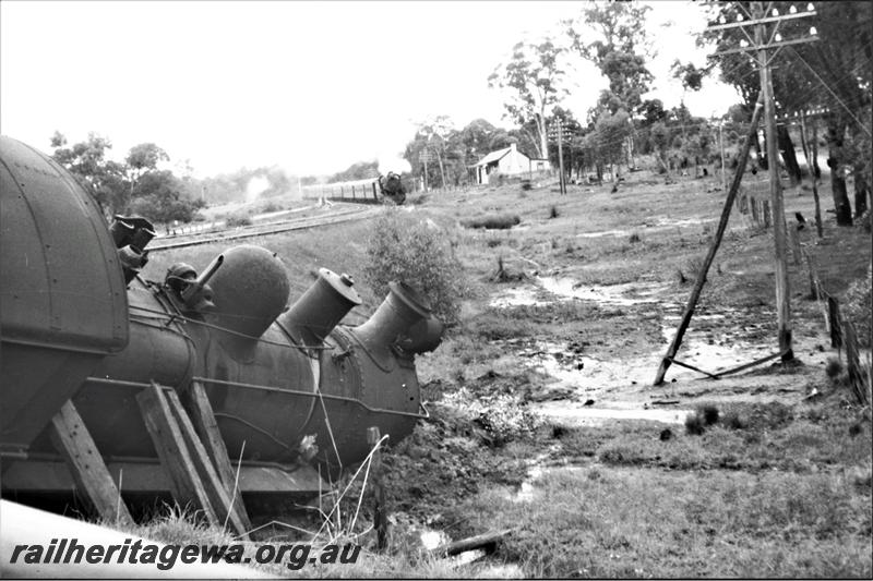 P21590
Derailment of E class loco, engine supported by sleepers, another passenger train approaching, building, Wooroloo, ER line, trackside view
