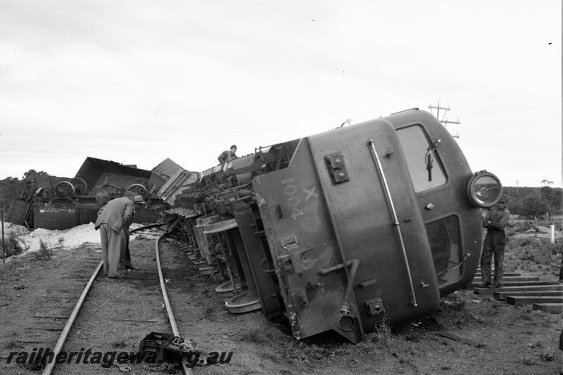 P21598
X class 1004 derailed, lying on side, wagons from No 94 goods train also derailed and lying across track, onlookers, 195mile 45chains, EGR line ,front view from track level 
