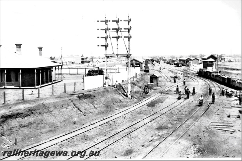 P21931
Bracket of ten semaphore signals, signal box, trackside house, tracks, sidings, sheds, train, Kalgoorlie, EGR line, view from elevated position
