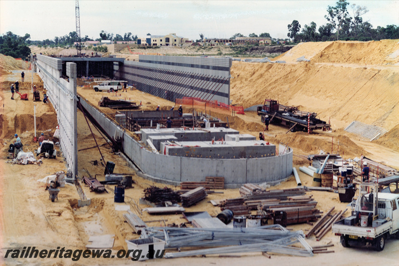 P22038
Construction of Joondalup interchange station, retaining walls, trucks, building materials, workers, Joondalup line, view form elevated position, NSR Line
