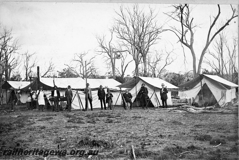 P22182
Bush camp, Narrogin to Dwarda Railway Survey, men pictured in front of their tents (from left to right): J. Moore, J. Relph, D. Hutchinson, V. Barber, R.J. Gordon, A. G. Thompson, J. T. Burnett, G. McIntyre, S.A. Hill, PN line, group photo
