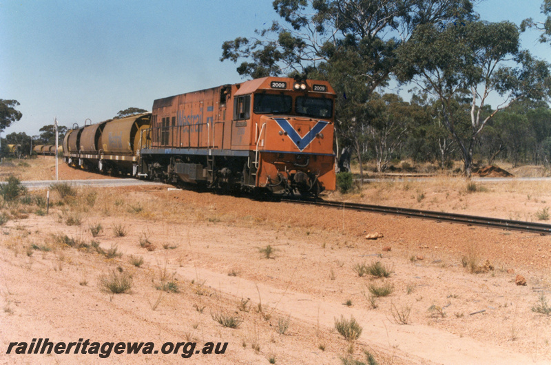 P22189
P class 2009 on wheat train comprising XW class wagons, passing level crossing on Goldfield Road, Wyalkatchem, GM line, side and front view
