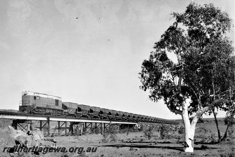 P22197
Goldsworthy Mining A class diesel loco, similar to the WAGR K class loco,  on train of empty ore wagons, crossing Turner River bridge, Pilbara, front and side view
