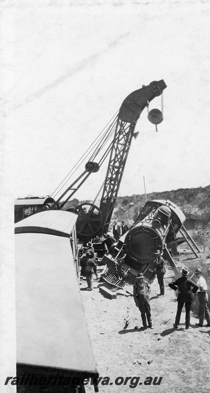 P22261
Derailment at 169 mile near Bruce Rock YB line No 4 of 7, Cravens 25 ton breakdown crane No.23, L class 240 loco propped up with wooden supports, wagons, onlookers, elevated view
