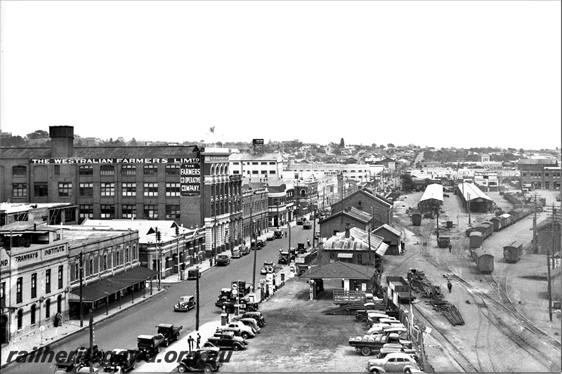 P22364
View of Perth Goods Yard, sheds, tracks, Westralian Farmers Limited building, Tramways Institute building, car park, Wellington Street,  Perth, ER line, view from elevated position looking west
