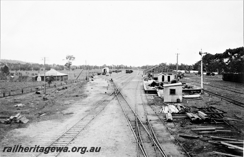 P22371
Construction of station building at Brunswick Junction SWR line 4 of 4, partly completed building, platform, points, crossovers, yard, wagons, shed, building materials, signal, trackside buildings, view from elevated position
