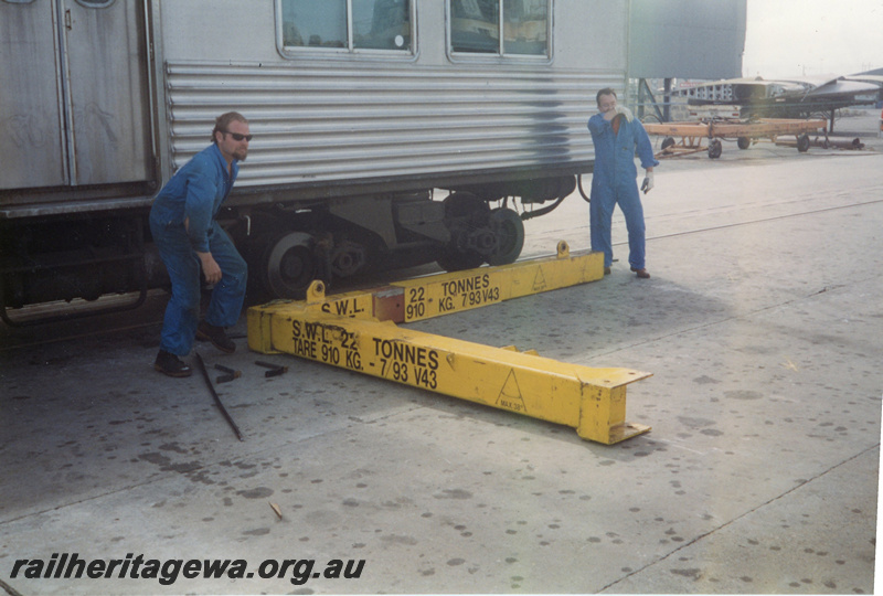 P22414
ADK class railcar, bogie cradle being prepared by workers, prior to lifting onto ship 