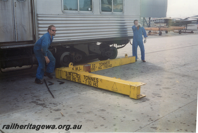 P22414
ADK class railcar, bogie cradle being prepared by workers, prior to lifting onto ship 