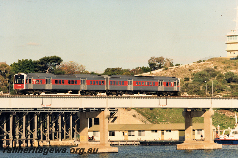 P22445
Transperth suburban DMU comprising ADL class 809 and ADC class 859, crossing Fremantle rail bridge, Swan River, boat, port control tower, sheds, end and side view 
