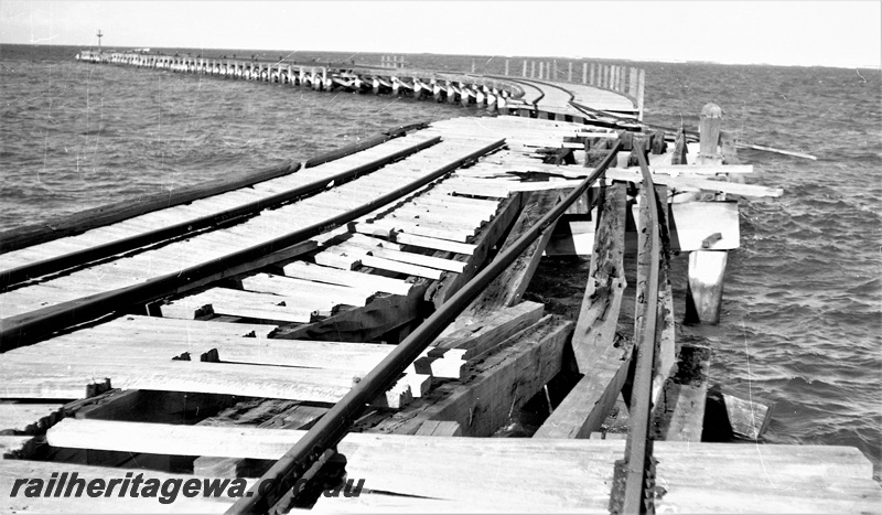 P22471
Storm damage to rails on Hopetoun jetty HR line 5 of 6, damage to planks, supports and rails, view from jetty looking seawards
