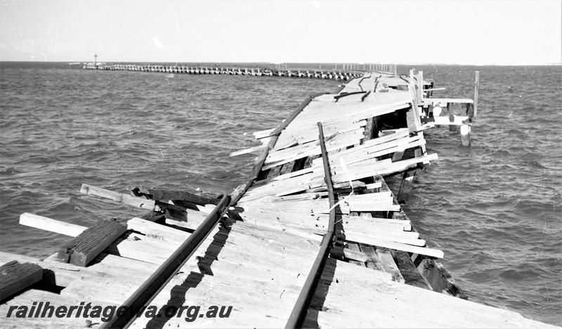 P22472
Storm damage to rails on Hopetoun jetty HR line 6 of 6, jetty and rails twisted out of shape, view from jetty looking seawards
