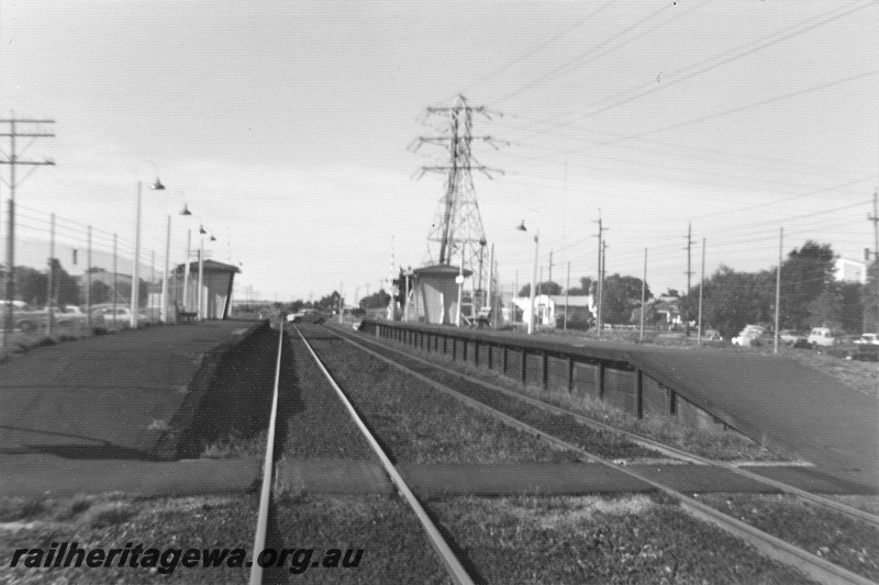 P22475
Oats Street station SWR line 3 of 5, both platforms, shelter sheds, rails, power pylon, telegraph pole, station lights, pedestrian path across tracks, view looking along the tracks from track level, c1976-1977
