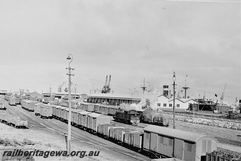 P22576
D class 378, rakes of vans and wagons including VB class 13330, sidings, warehouses, wharves, ships, Fremantle yard, ER line, side and end view, c1955
