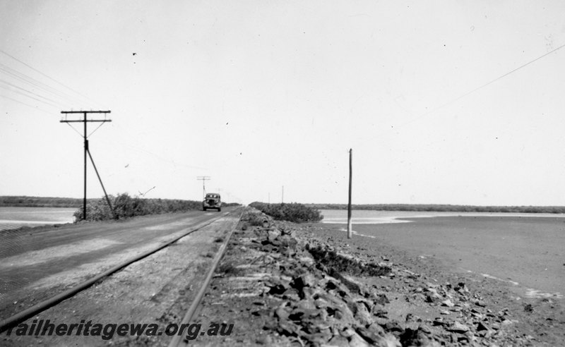 P22749
Track next to road, running along embankment near sea, motor car, Port Hedland, PM line, c1950s
