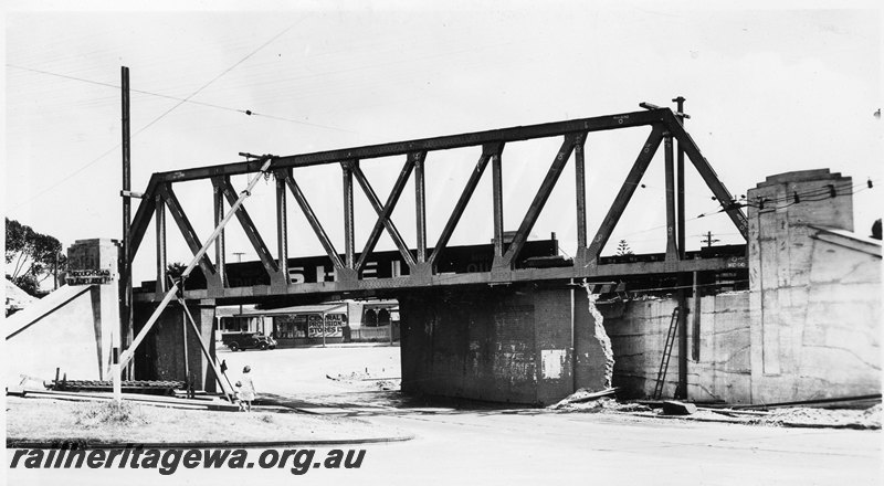 P22756
Extension of Mt Lawley subway ER line No 5 of 15, side trusses with stays, partly demolished subway wall, onlooker, shops, truck, view along roadway passing through subway looking west
