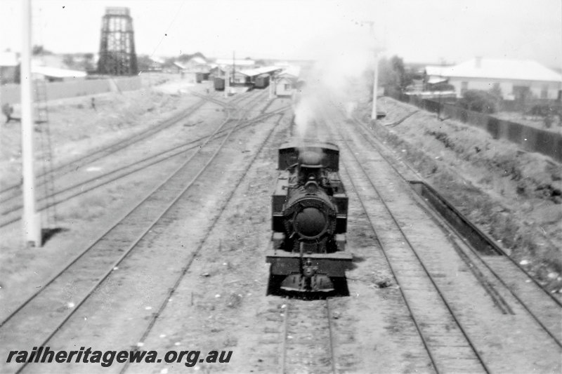 P22796
K class loco, signals, station buildings, platforms, water tower, houses, Kalgoorlie, EGR line, front view taken from Maritana Street bridge, c1952
