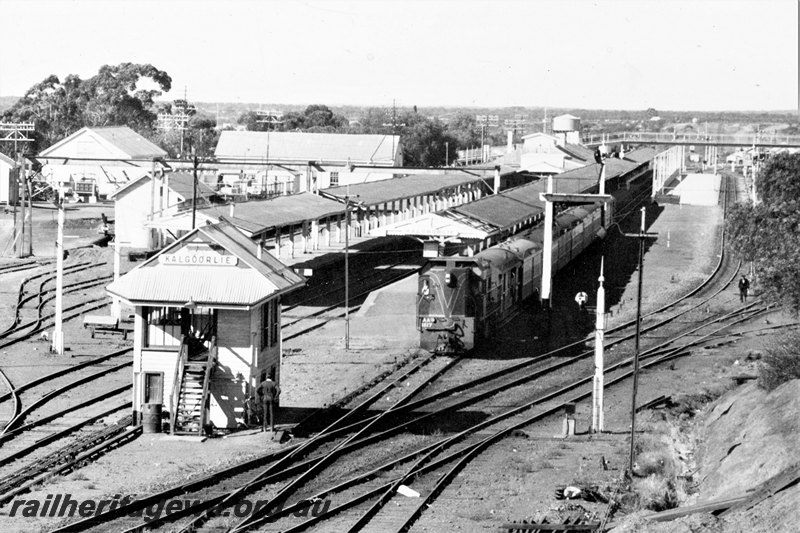 P22799
AA class 1517, pulling carriages away from platform to carriage shed, station buildings, signal box, sidings, platforms, canopies, overhead footbridge, signals, water tower, Kalgoorlie, EGR line, front and side view from elevated position 
