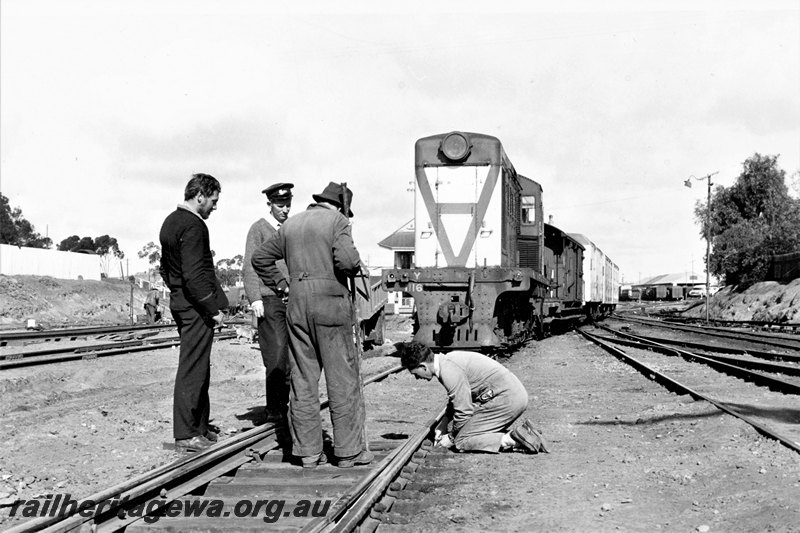P22800
Y class 1116, on yard duties, workers making preparations for laying of standard gauge connection and mixed gauge diamond crossing, near signal box B, Kalgoorlie, EGR line, view from trackside 
