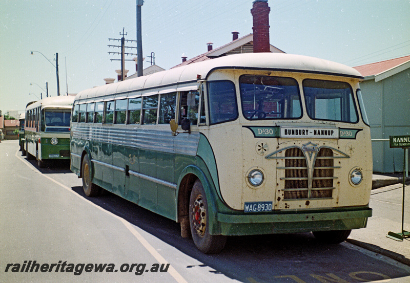 P24208
Railway Road Service  bus Daimler DA30 WAG8930 destined for Nannup, front portion of another bus, buildings fronting roadway, Bunbury, SWR line, side and front view
