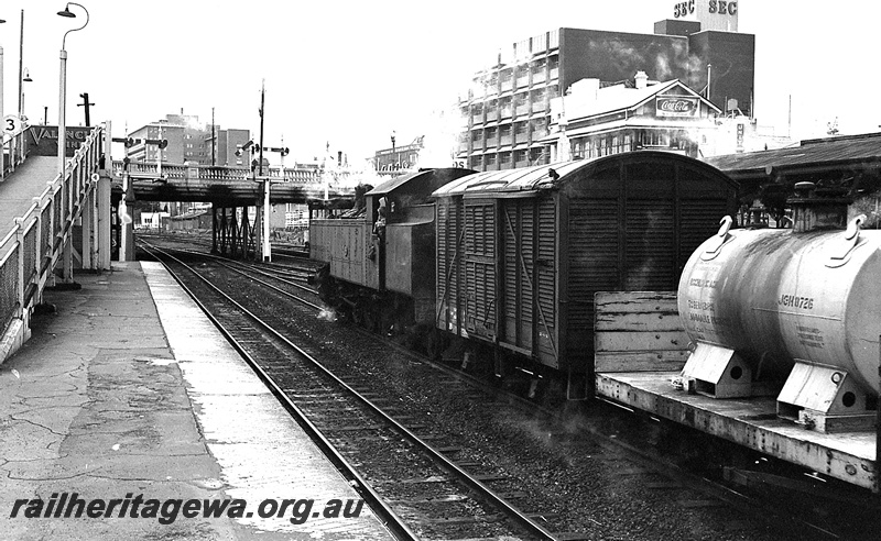 P24248
DD class 596, on louvre wagon, and flat wagon with tank JGH class 8726 used for Hydrochloric Acid storage, platform, canopies, pedestrian ramp, overhead road bridge, bracket signals, buildings in background, Perth city station, side and rear view from platform
