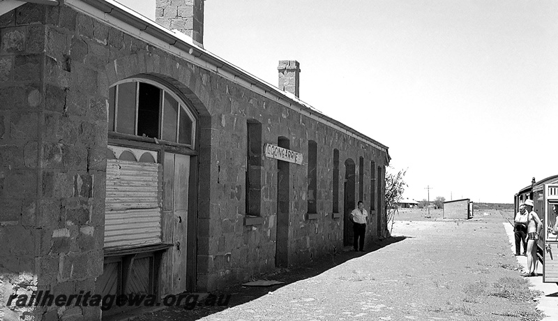 P24283
Station building, stone wall, no eaves, trackside building, carriages at platform, three pedestrians, Goongarrie, KL line, view from platform
