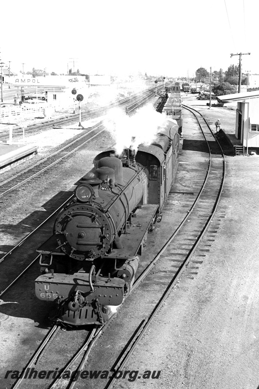 P24366
U class 655, on goods train, platform, light signals, goods shed 4th class, Ampol garage, Bassendean, ER line, front and side view from an elevated position
