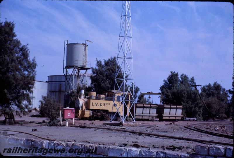 T03686
Lake View & Star Ltd. Loco, Orenstein & Koppel 0-6-0T, builders No.4242, yellow livery with black lettering, hoppers behind the loco, fire hose box in the foreground, Great Boulder mine, Kalgoorlie, front and side view. 
